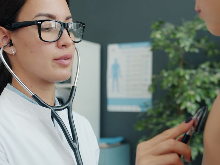 Médica auscultando a un paciente con estetoscopio